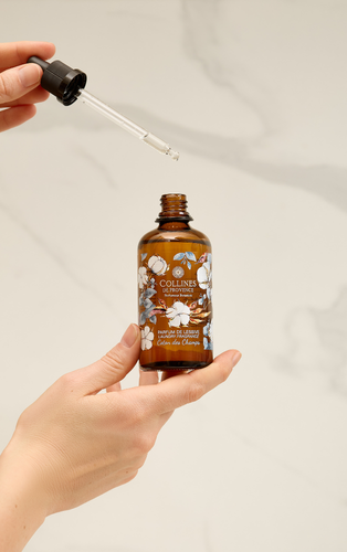 Une main dose le parfum de lessive à la pipette au-dessus du flacon